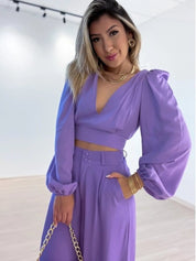 Paarse tweedelige set, bestaande uit een top met lange mouwen en een stijlvolle V-hals, samen met een broek met comfortabele rechte pijpen en een mid-rise taille. Perfect voor diverse gelegenheden. Stel moeiteloos en modieus je outfit samen met deze prachtige set.