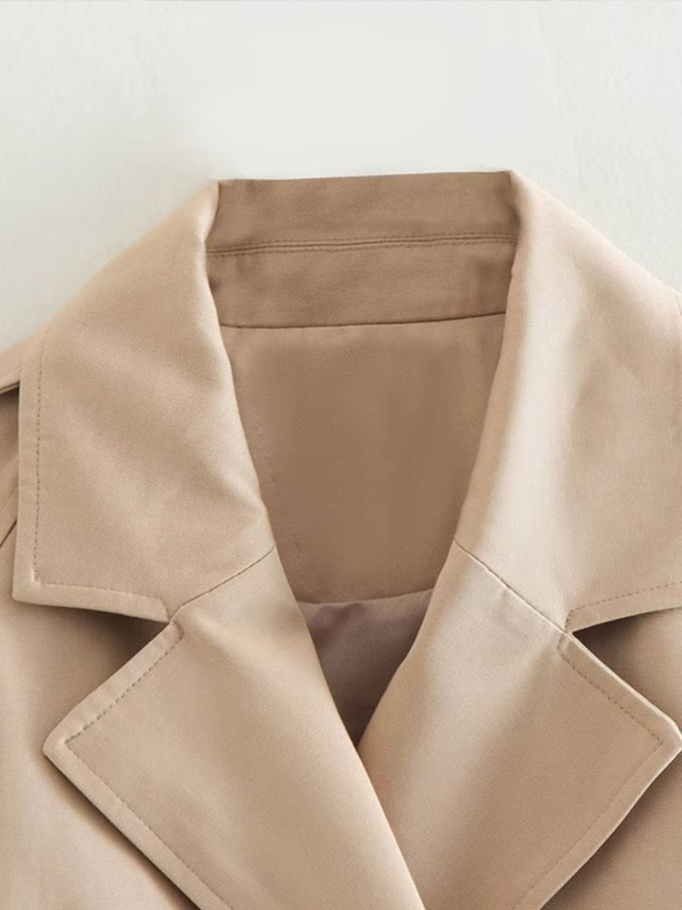 Beige cropped trenchcoat - een must-have voor een stijlvolle look. Voorzien van een double-breasted sluiting, kraag en verstelbare mouwen met manchetten voor een trendy uitstraling. Voeg moeiteloos een vleugje elegantie en professionele flair toe aan elke outfit.